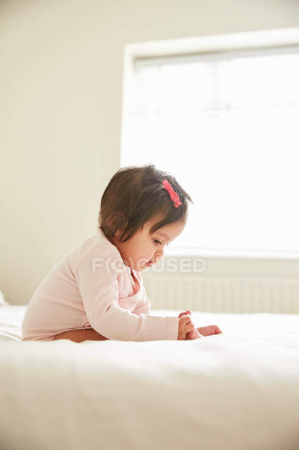 Девочка, сидящая на кровати — стоковое фото