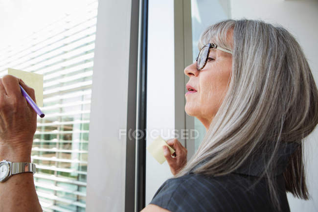 Femme d'affaires écrivant des idées sur fenêtre en verre — Photo de stock