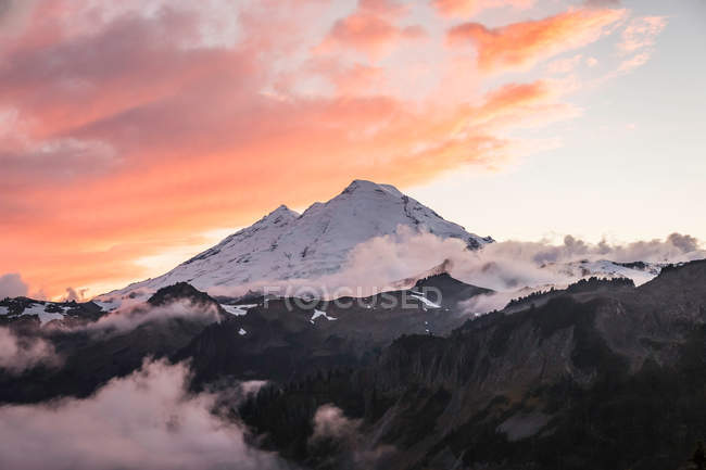 Clouds on snow covered mountains — Stock Photo