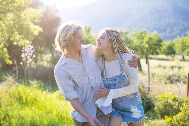 Couple riant tout en se promenant dans le champ rural — Photo de stock