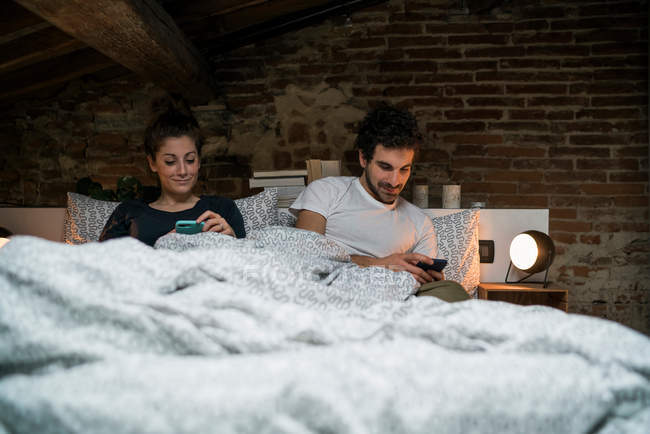 Couple sitting up in bed — Stock Photo