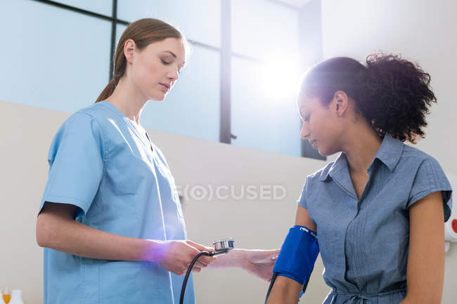 Médico tomando presión arterial del paciente - foto de stock