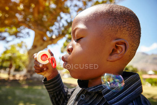 Хлопчик дме бульбашки в парку — стокове фото