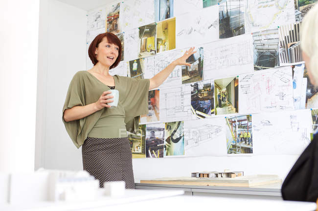 Женщина-архитектор указывает на доску настроения — стоковое фото