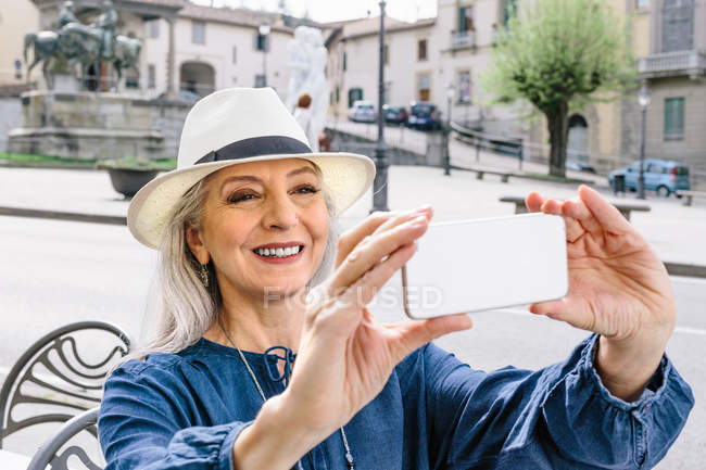 Woman taking smartphone selfie at sidewalk cafe — Stock Photo