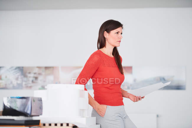 Businesswoman in office holding blueprints — Stock Photo