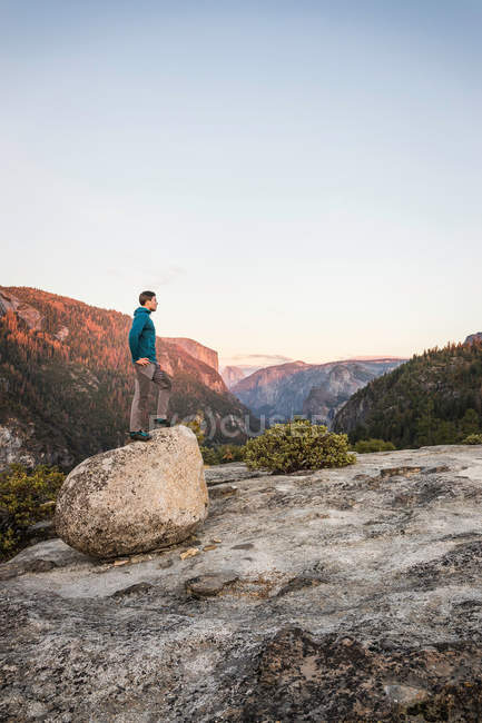 Hombre mirando desde la cima de la roca - foto de stock