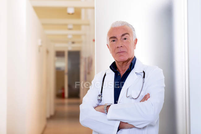 Доктор со сложенными руками смотрит в камеру — стоковое фото