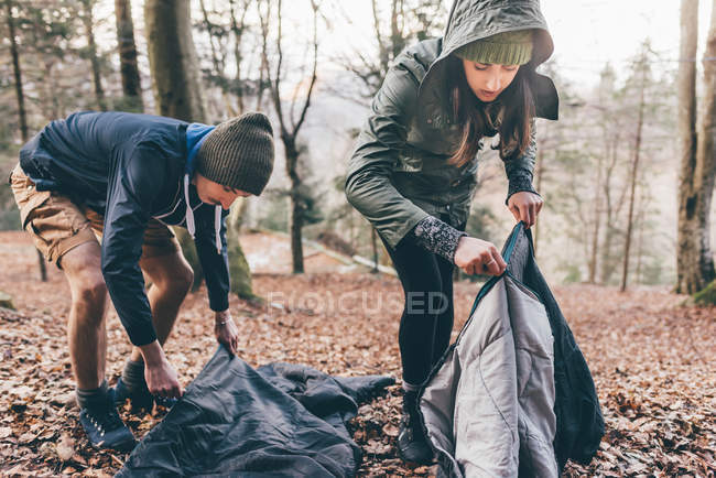 Hiking couple packing sleeping bags — Stock Photo