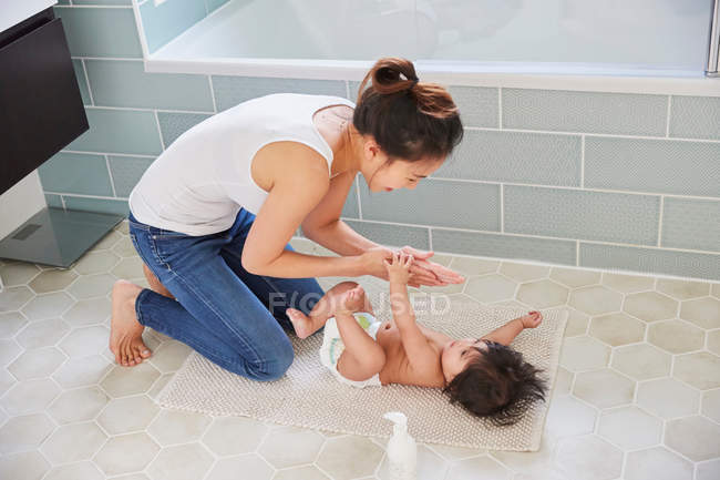 Woman applying moisturiser to baby daughter — Stock Photo