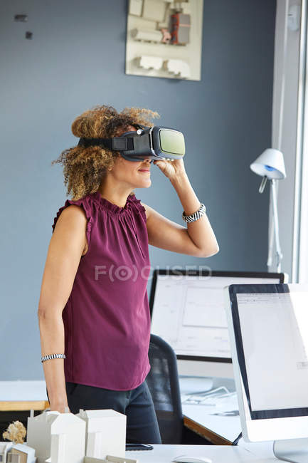 Mujer mirando a través de auriculares de realidad virtual - foto de stock