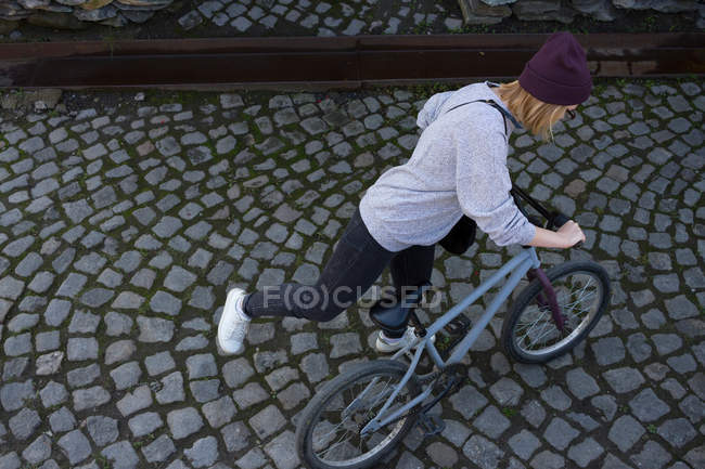 Молода жінка монтує велосипед BMX — стокове фото