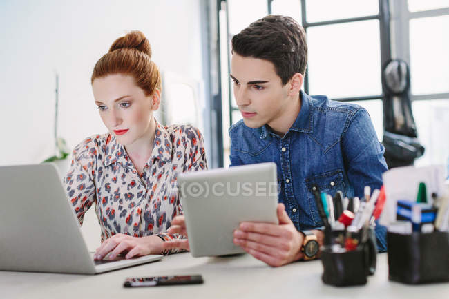 Colleagues using digital tablet and laptop — Stock Photo