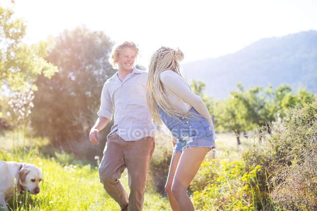 Пара смеется во время выгула собаки в сельской местности — стоковое фото