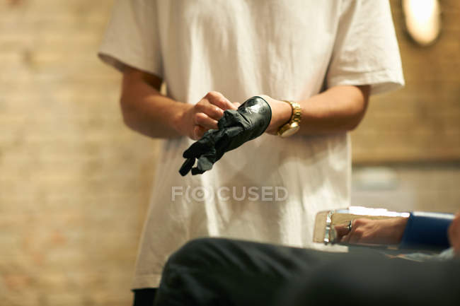 Hairdresser putting on latex glove — Stock Photo