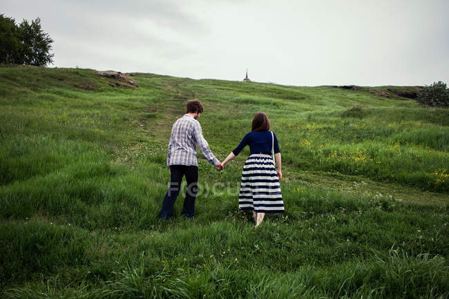 Casal andando por uma colina gramada — Fotografia de Stock