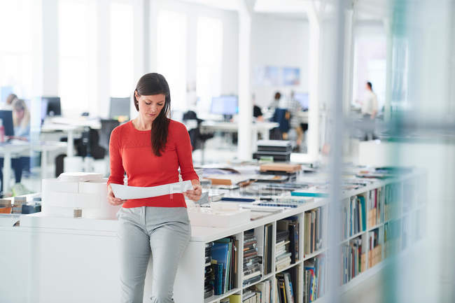 Businesswoman in office looking at blueprints — Stock Photo