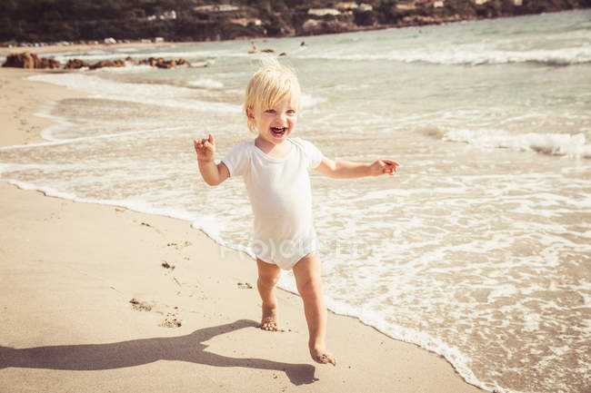 Giovane ragazzo a piedi lungo la spiaggia — Foto stock