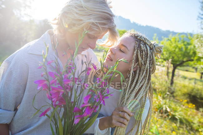 Romântico jovem casal com flores silvestres no campo — Fotografia de Stock