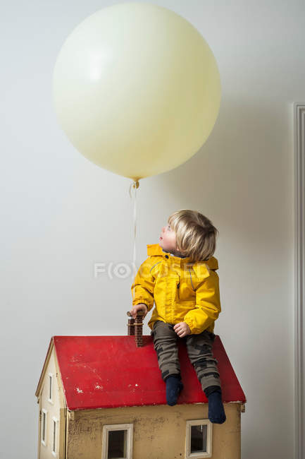Мальчик сидит на кукольном домике — стоковое фото
