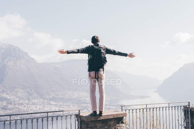 Чоловік стоїть на стіні тераси над гірським берегом озера — стокове фото