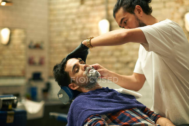 Cabeleireiro dando ao cliente barba molhada — Fotografia de Stock