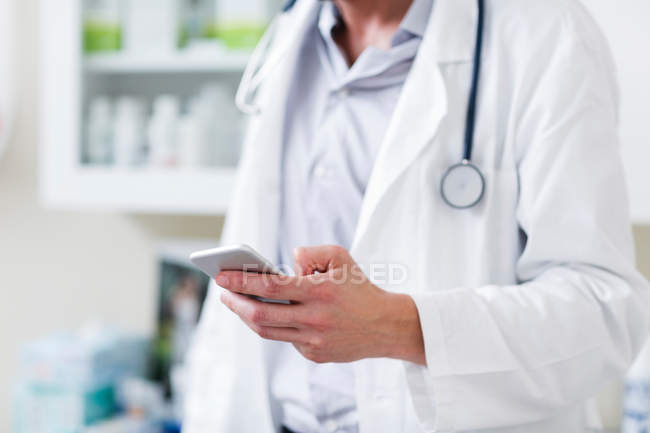 Лікар в лікарні тримає мобільний телефон — стокове фото