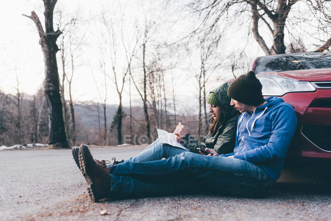 Hiking couple sitting on roadside — Stock Photo