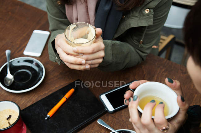 Young women cupping coffee in cafe — Stock Photo