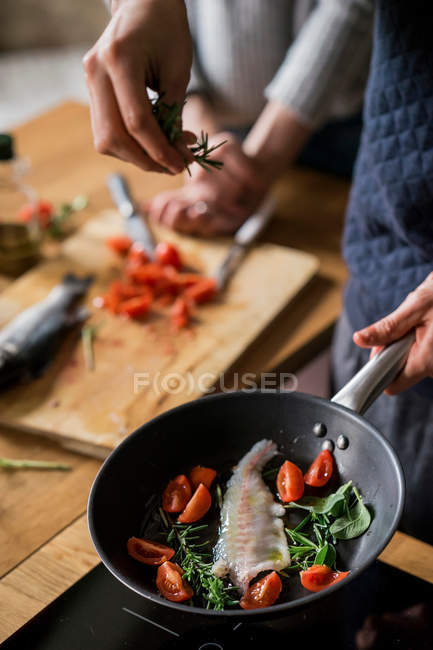 Couple frying fish with herbs — Stock Photo