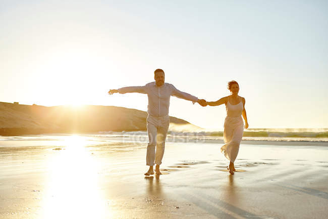 Mature couple walking along beach — Stock Photo