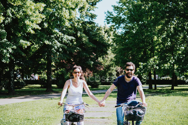 Paar hält sich beim Radfahren im Park an der Hand — Stockfoto