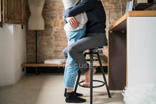 Hombre abrazando novia de cocina taburete - foto de stock