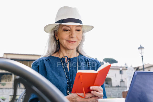 Woman looking at notebook at sidewalk cafe — Stock Photo
