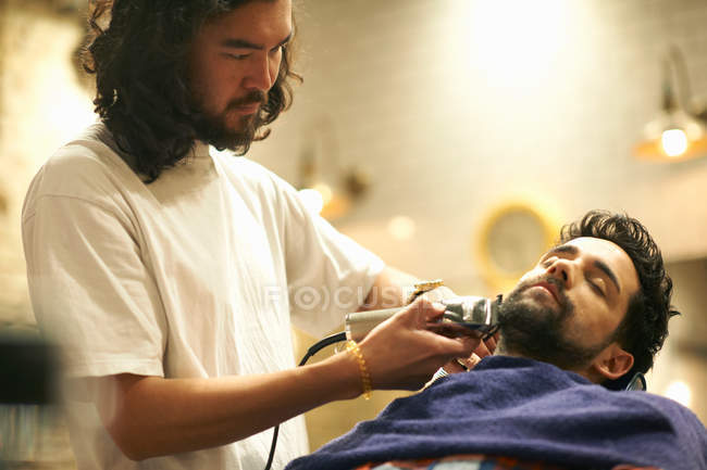 Hairdresser shaving customers beard — Stock Photo