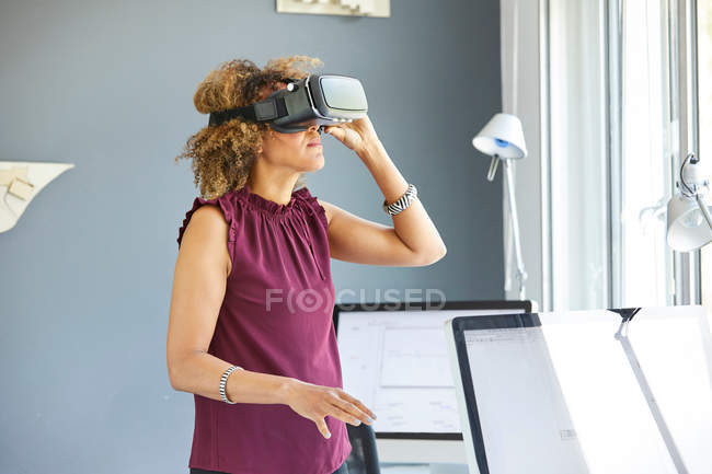 Mujer mirando a través de auriculares de realidad virtual - foto de stock