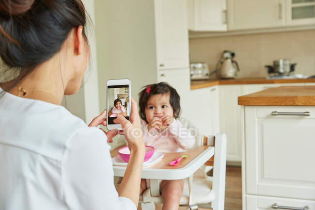 Woman photographing baby daughter — Stock Photo