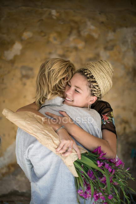 Cople avec un bouquet de fleurs étreignant — Photo de stock