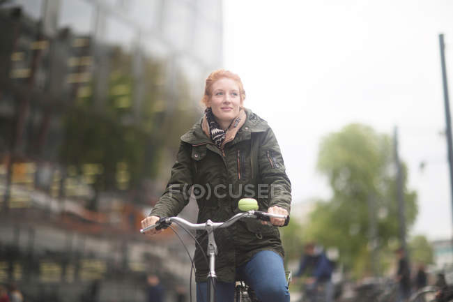 Estudiante en bicicleta lejos de la Biblioteca Universitaria - foto de stock