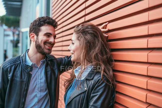 Couple chatting by orange wall — Stock Photo