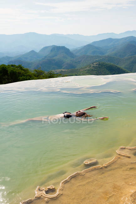 Woman floating in thermal spring — Stock Photo