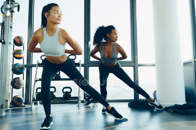 Dos mujeres jóvenes haciendo ejercicio en el gimnasio - foto de stock