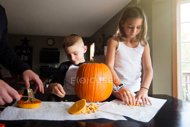 Pai e filhos esculpindo abóbora — Fotografia de Stock