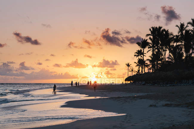 Personnes sur la plage au coucher du soleil — Photo de stock