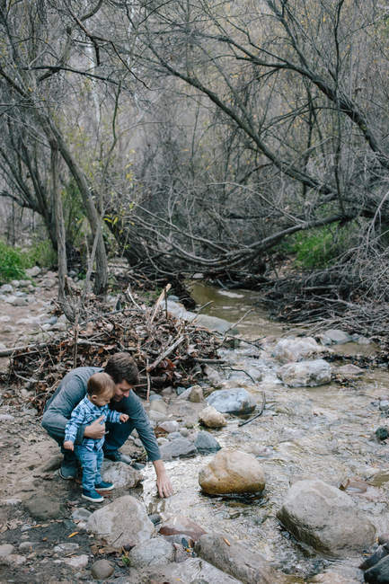Padre y bebé niño investigando río - foto de stock