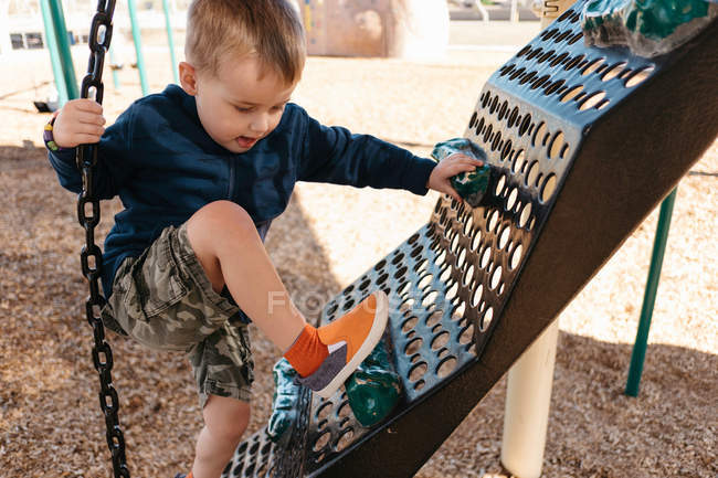 Rapaz a escalar no parque infantil a escalar quadro — Fotografia de Stock