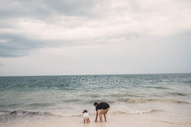 Pai e filha brincando com o mar — Fotografia de Stock