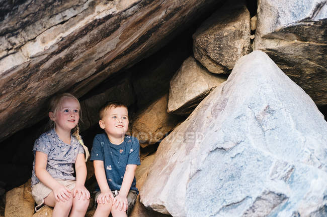 Ragazzo e ragazza seduti sulle rocce — Foto stock