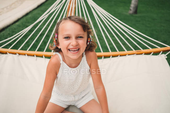 Girl sitting in hammock and smiling — Stock Photo