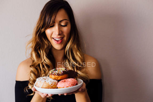 Jovem mulher segurando prato de donuts — Fotografia de Stock